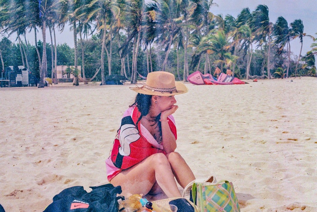 A woman sitting on a beach next to luggage