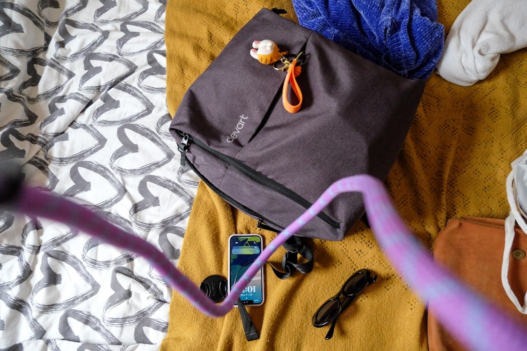 A bag, phone, and belongings are on a bed.