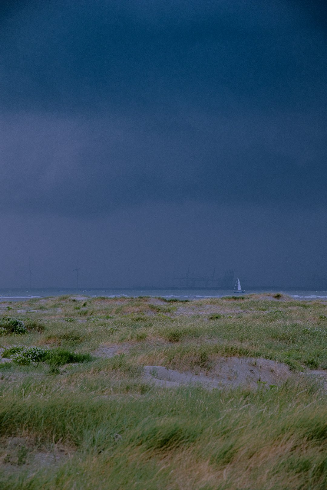 a lone sailboat in the distance on a cloudy day