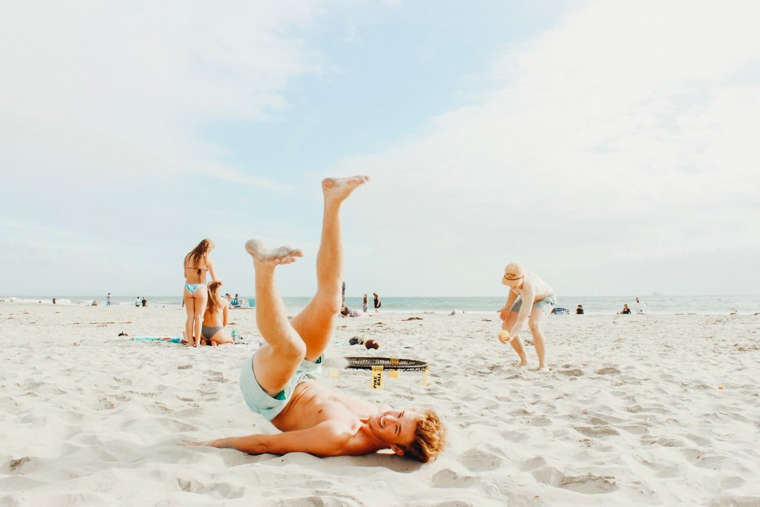 smiling man lying on white sand during daytime