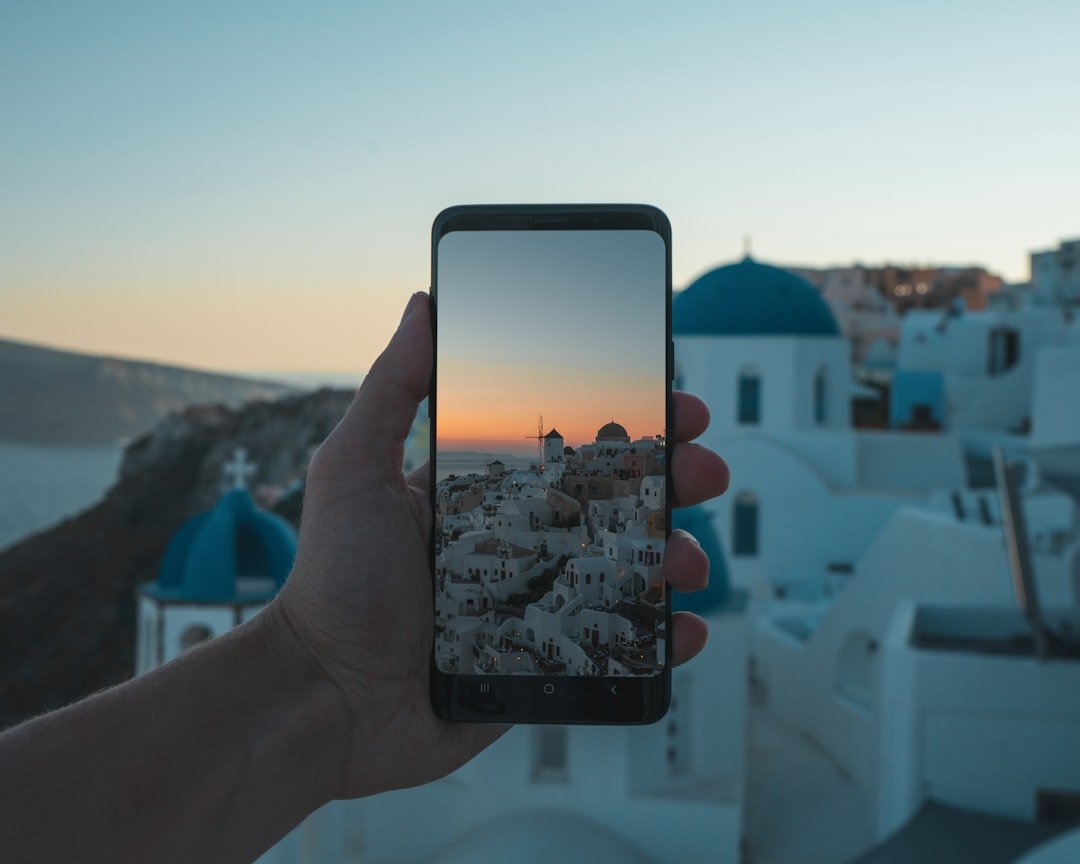 person holding black smartphone taking photo of city during daytime