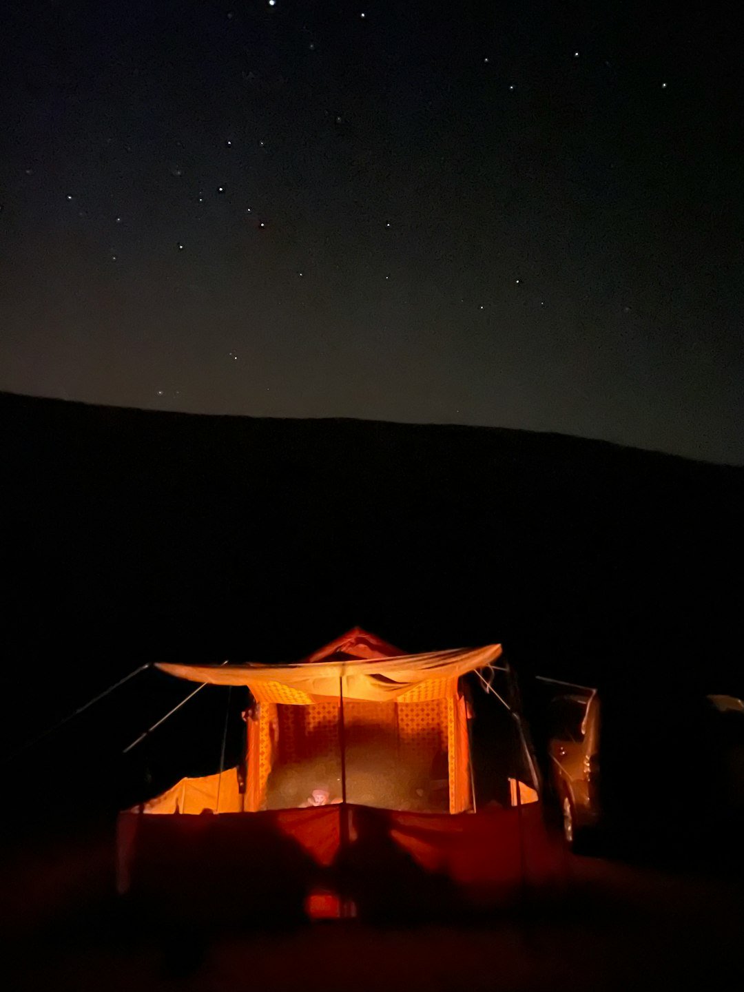 a tent is lit up at night with stars in the sky