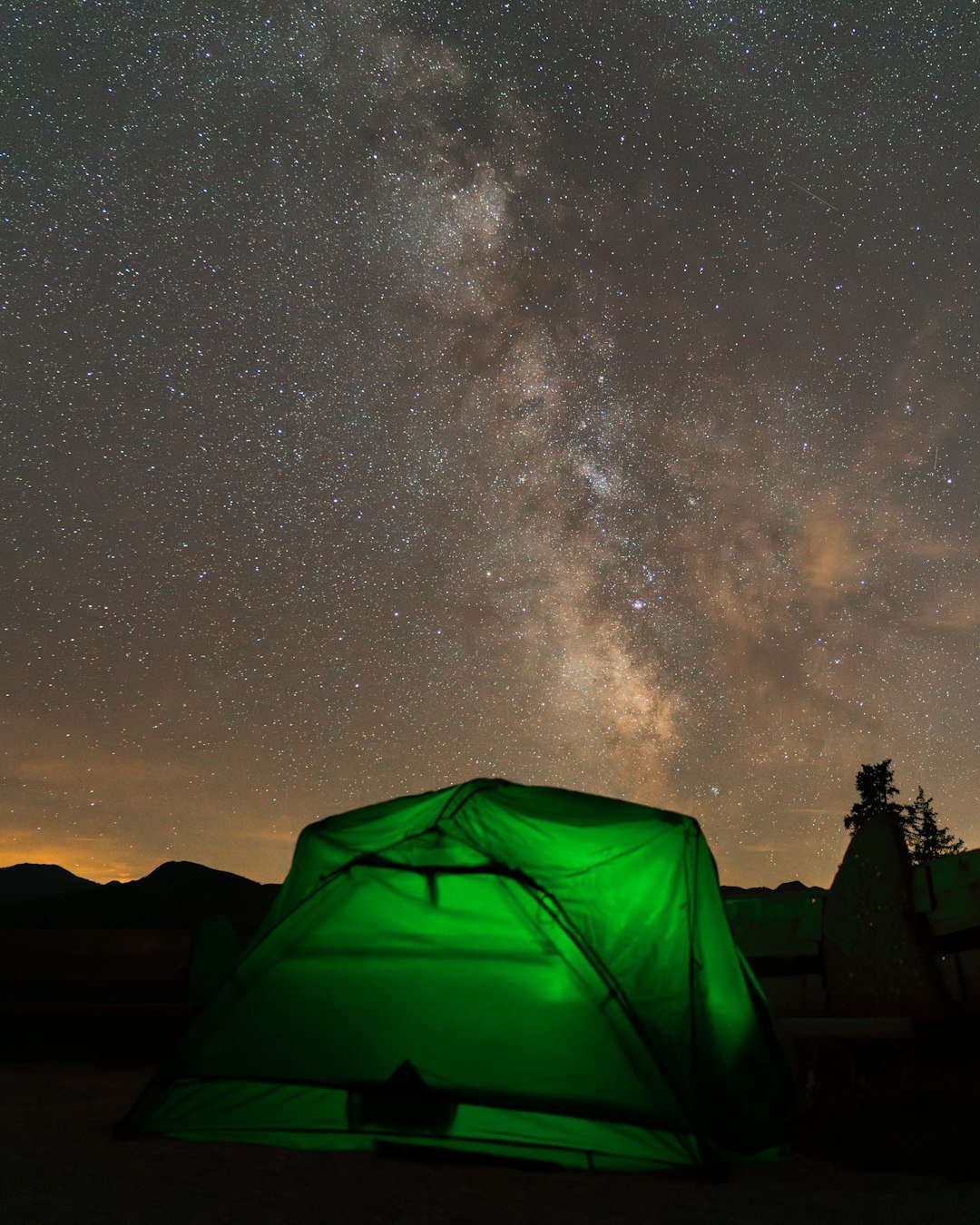 A green tent sitting under a night sky filled with stars