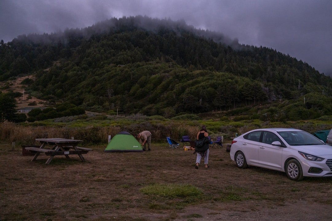 a woman and a man standing next to a tent and a car