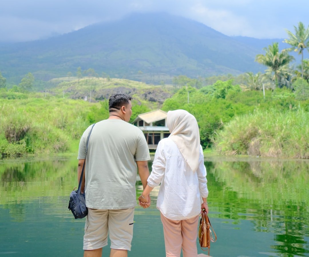 Couple holds hands and gazes at a scenic view.