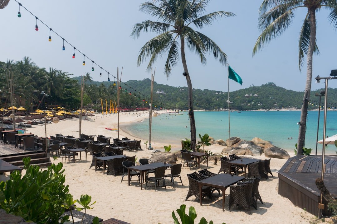 A sandy beach with tables and umbrellas on it