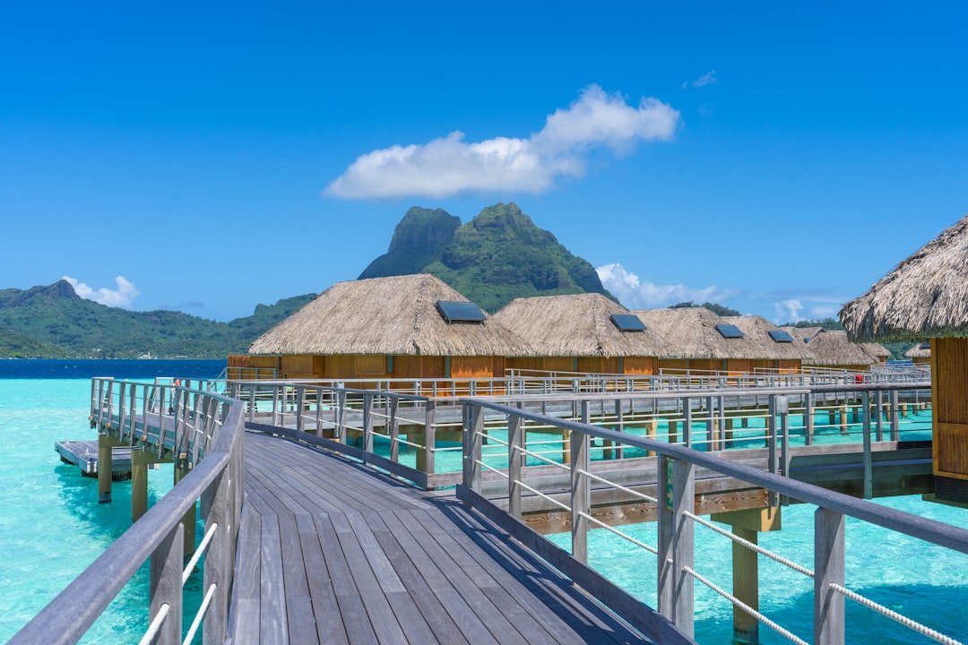 A wooden pier with thatched huts over water