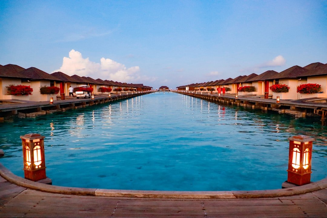 Overwater bungalows line a tranquil blue waterway.