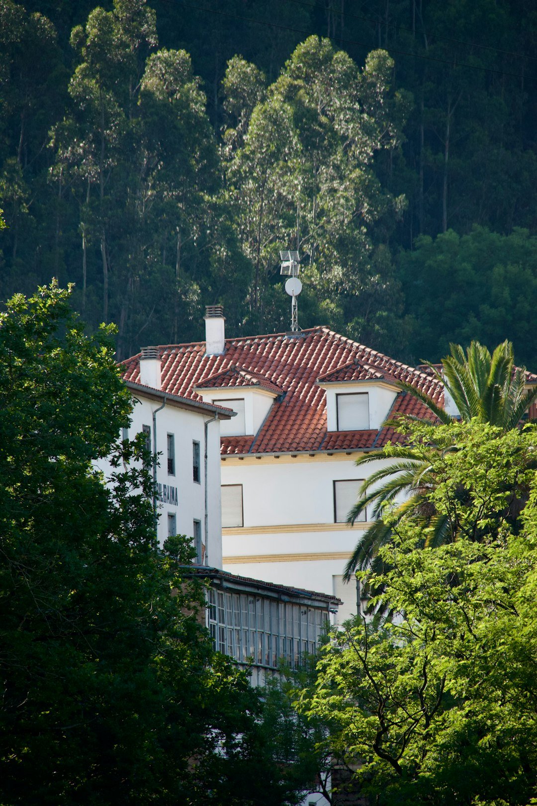a white house with a red roof surrounded by trees