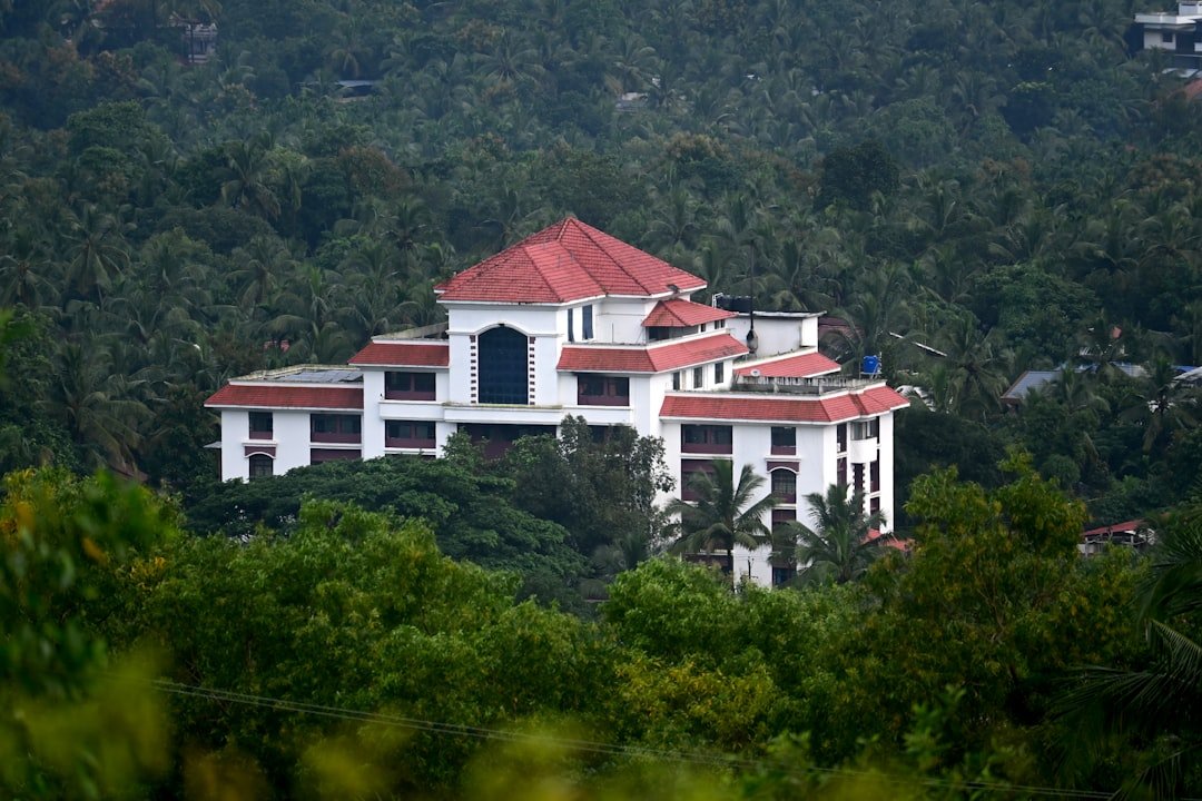 A large white building with a red roof surrounded by trees