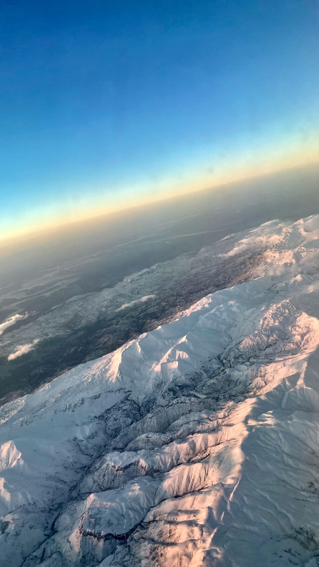 a view from an airplane of snow covered mountains
