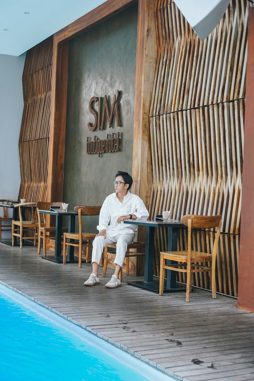 a man sitting at a table next to a swimming pool