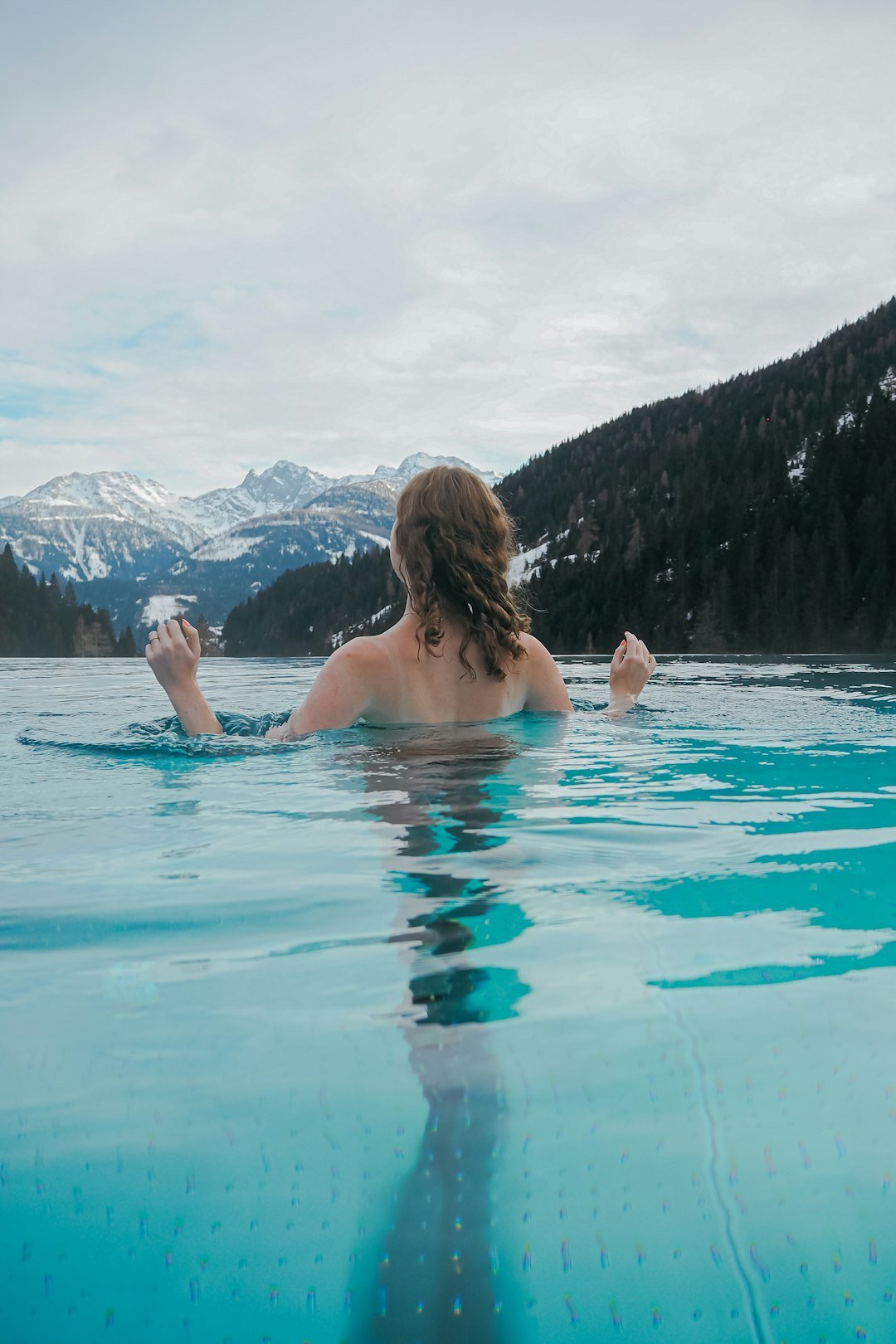 a woman swimming in a pool with mountains in the background