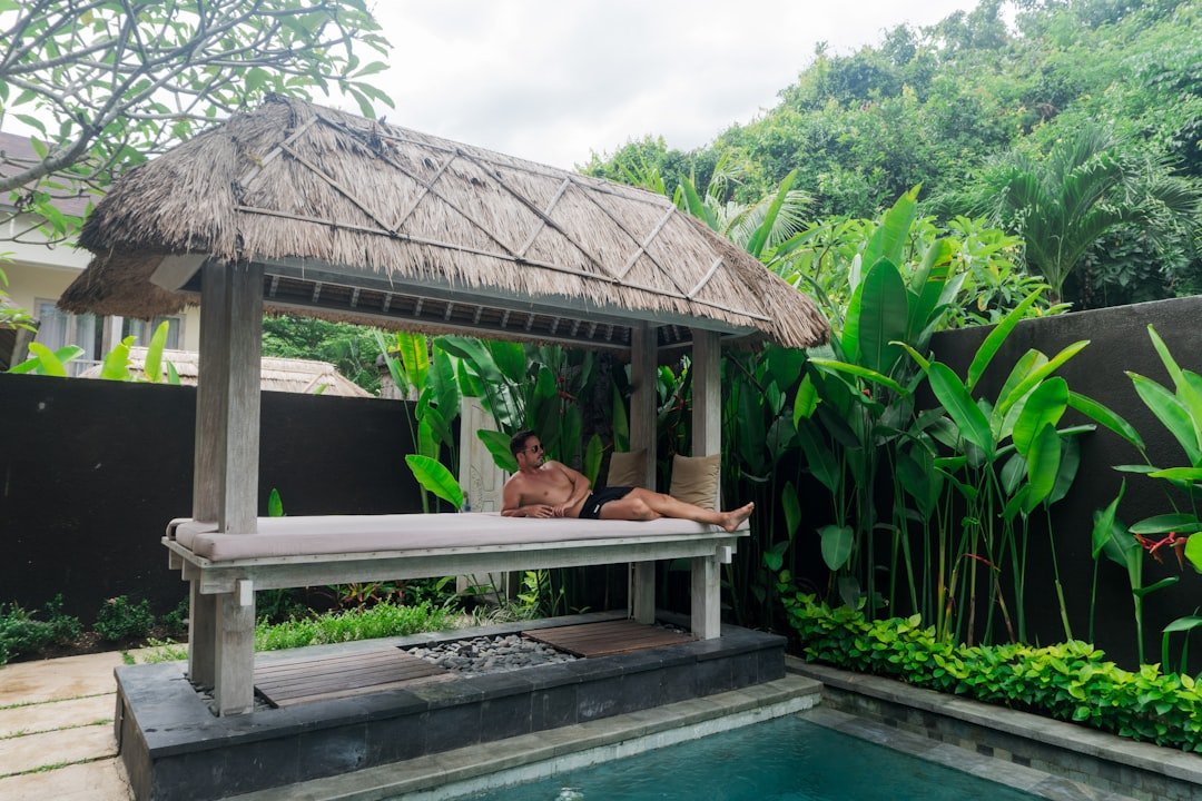A man laying on a bench next to a pool