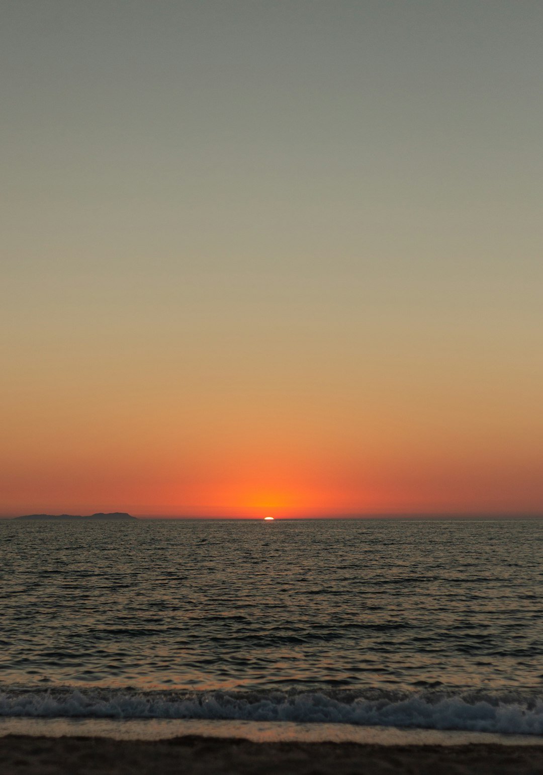 The sun is setting over the ocean on the beach