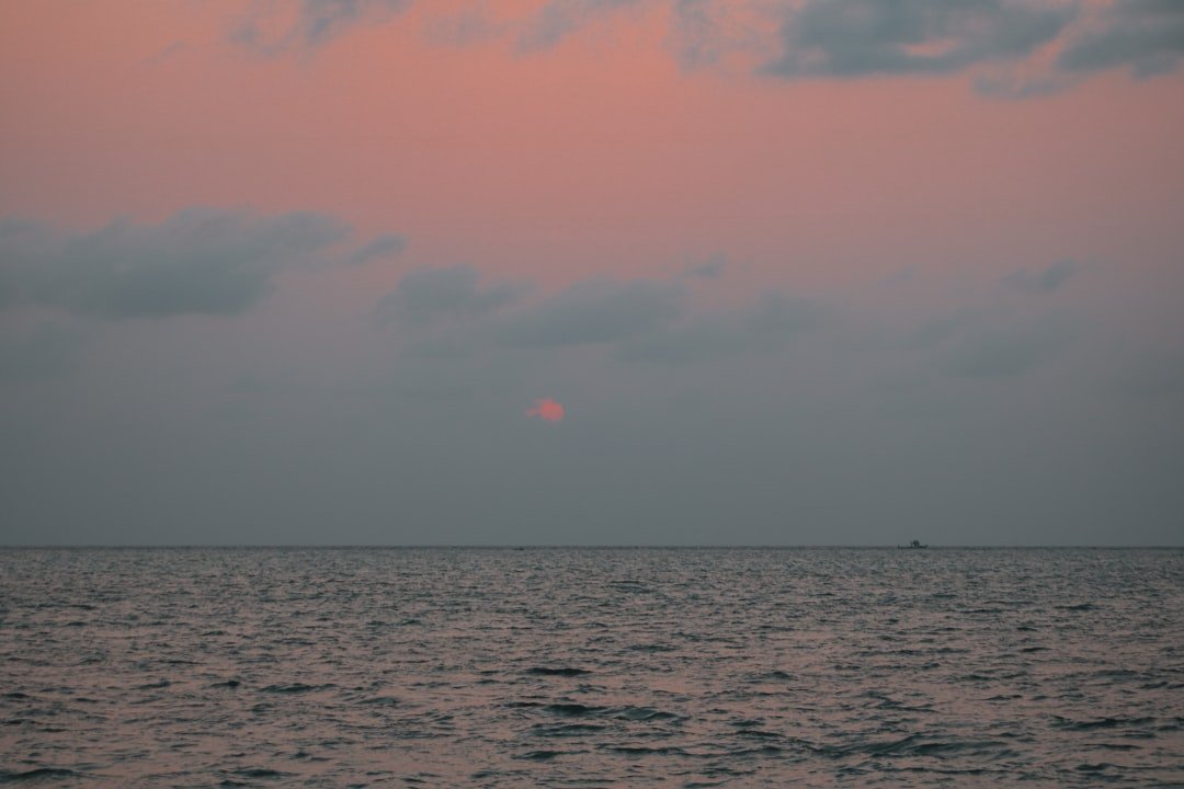the sun is setting over the ocean on a cloudy day