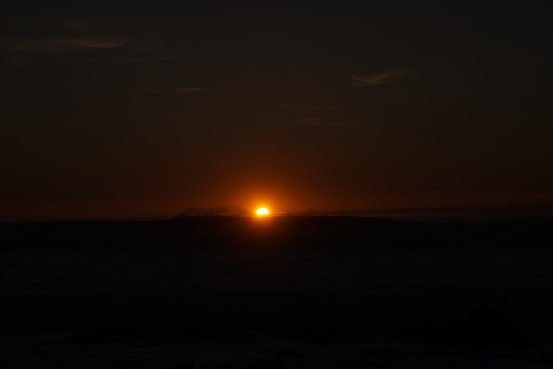 the sun is setting over the horizon of the ocean