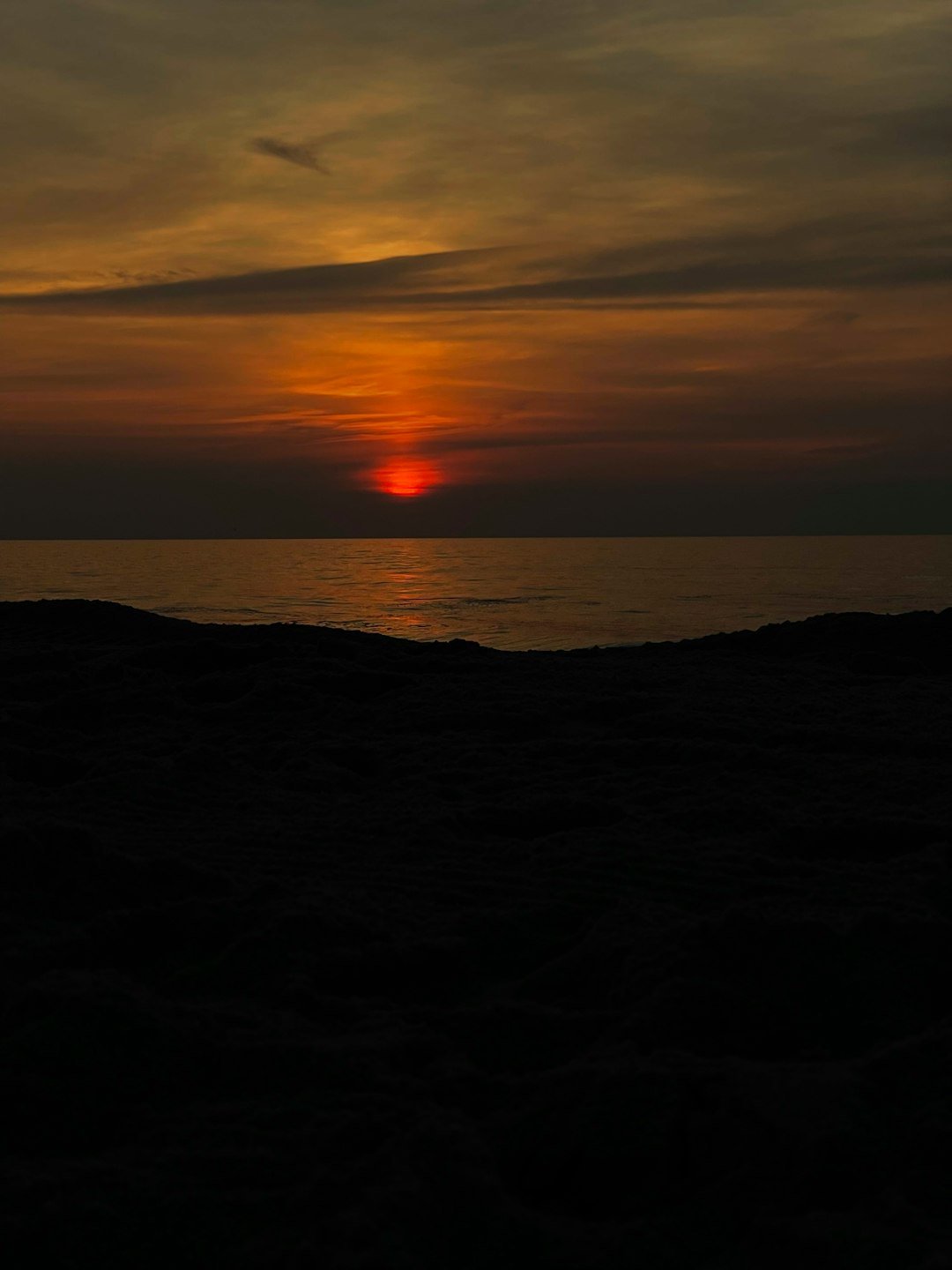 the sun is setting over the ocean on a cloudy day