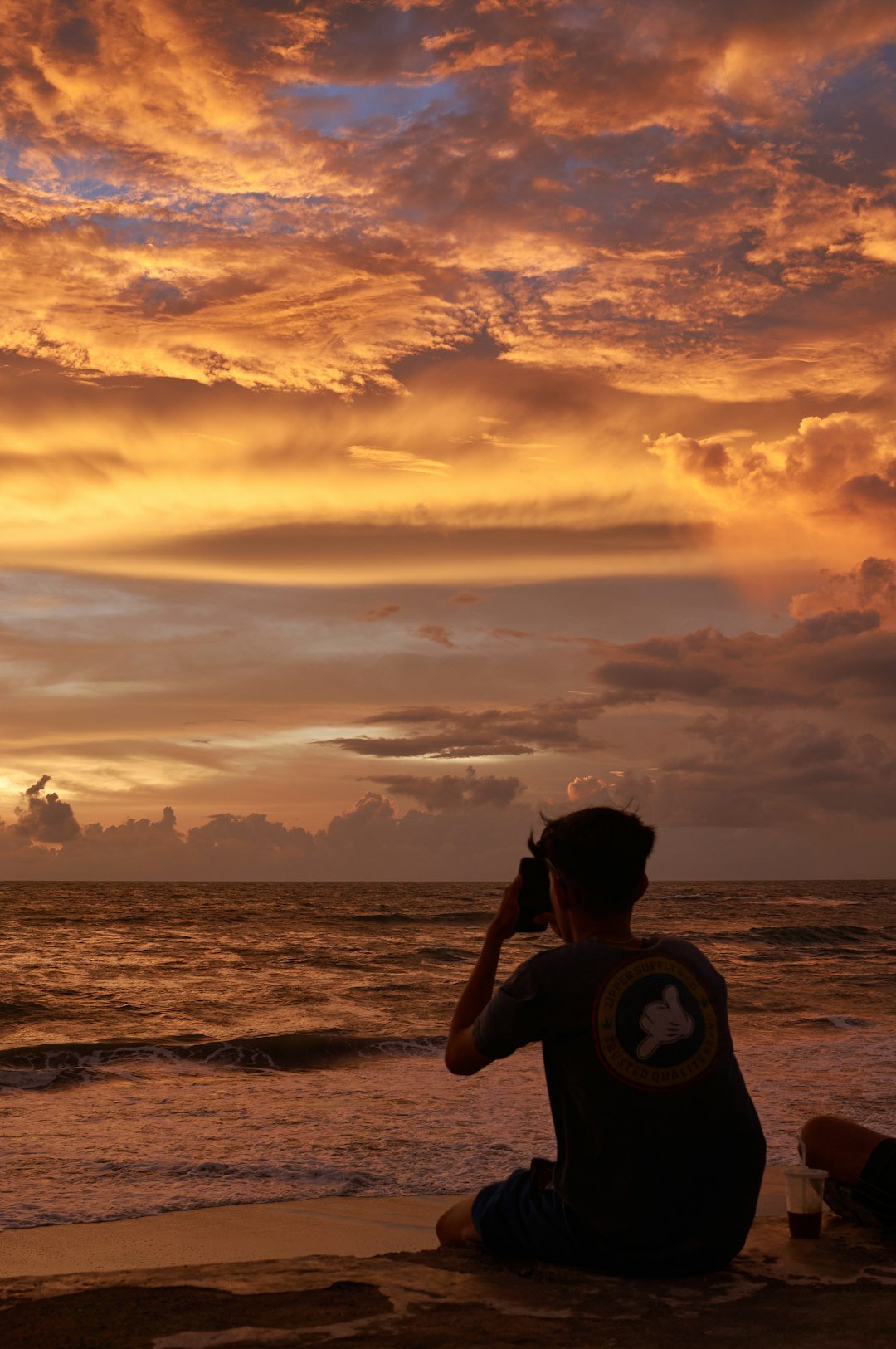 A man sitting on a beach watching the sunset