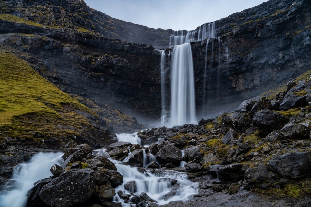 A majestic waterfall flows through rocky terrain.