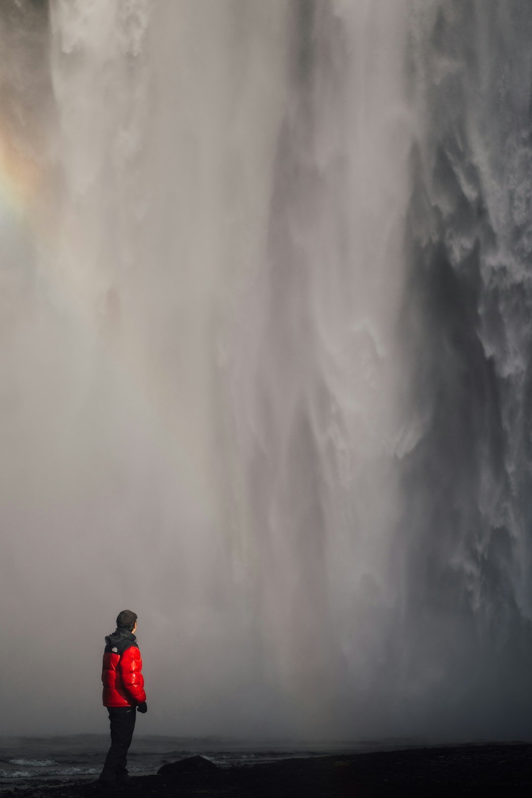 a person standing in front of a large waterfall