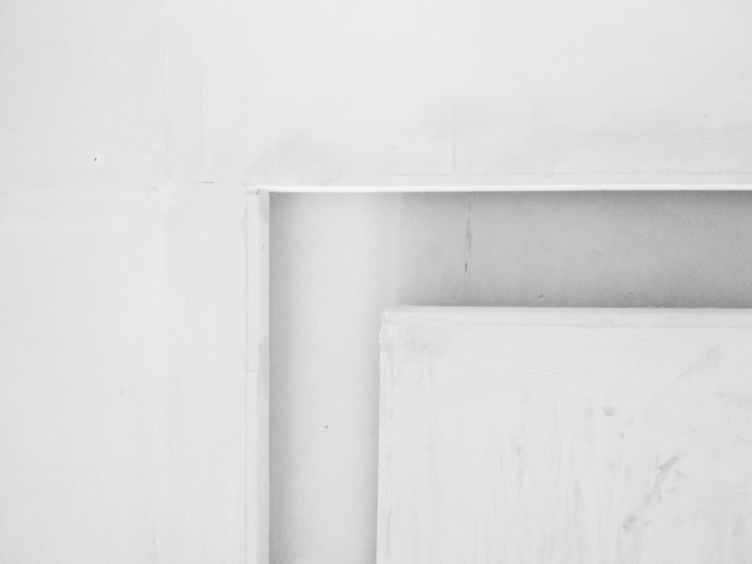 white wooden door on white concrete wall